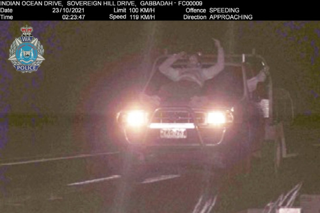 hombre bebiendo cerveza sobre el capó de un coche